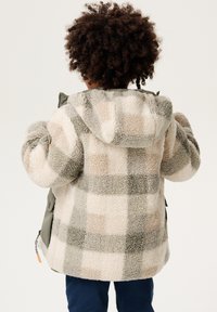 Flauschige, karierte Jacke mit grünen Akzenten; hat ein großes Karomuster in cremigen und grauen Tönen; verfügt über eine Kapuze und seitliche Taschen.