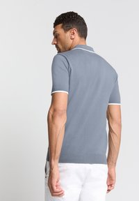 Grijze polo met korte mouwen en witte afwerking aan de mouwen en kraag. Gemaakt van een gestructureerde stof, met een getailleerd ontwerp.