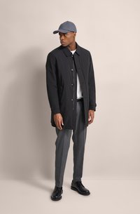 Schwarzer Knopf-unterer Mantel, graue Mütze, weißes Hemd, graue Hose und schwarze Schuhe. Einfaches Design mit glatter Textur und subtilen Details.