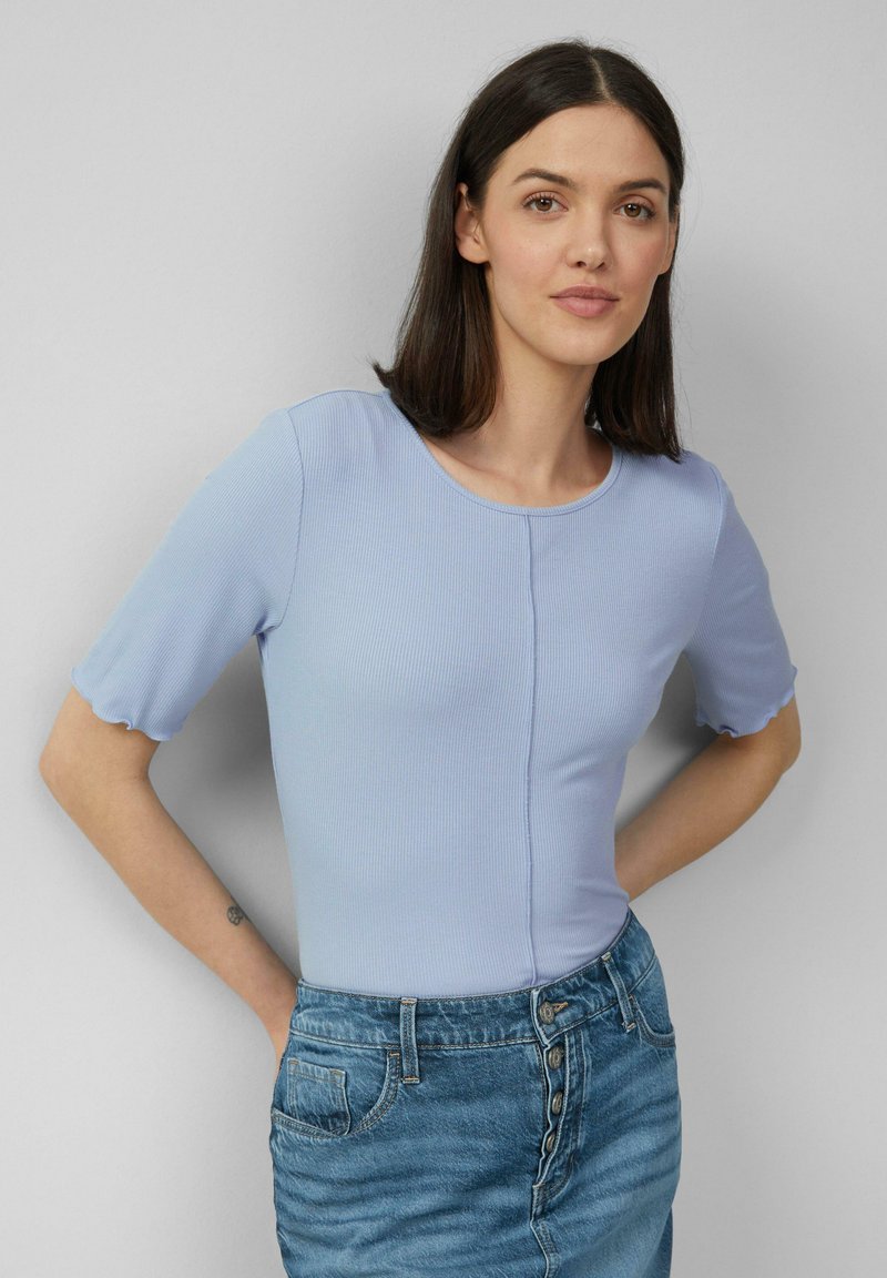 Jasnoniebieski prążkowany top z krótkimi, rozkloszowanymi rękawami i okrągłym dekoltem, w połączeniu z dżinsową spódnicą z przodu zapinaną na guziki i kieszeniami.