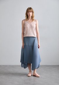 Sequined pink tank top with a v-neck design paired with a flowing, pleated light blue asymmetrical skirt and soft pink loafers.