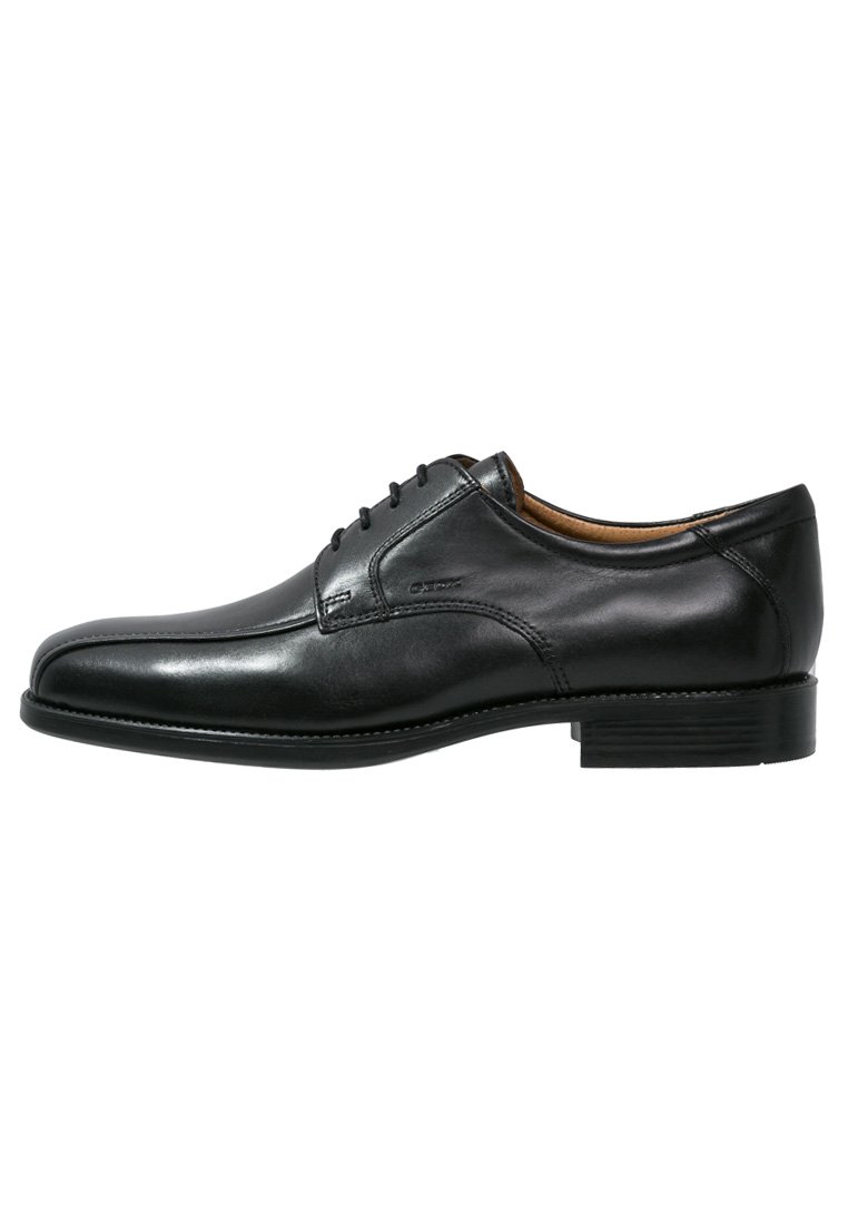 Zapato de vestir de cuero negro con un acabado suave, punta redondeada, seis ojales y un tacón bajo y apilado. Presenta detalles de costura mínimos.
