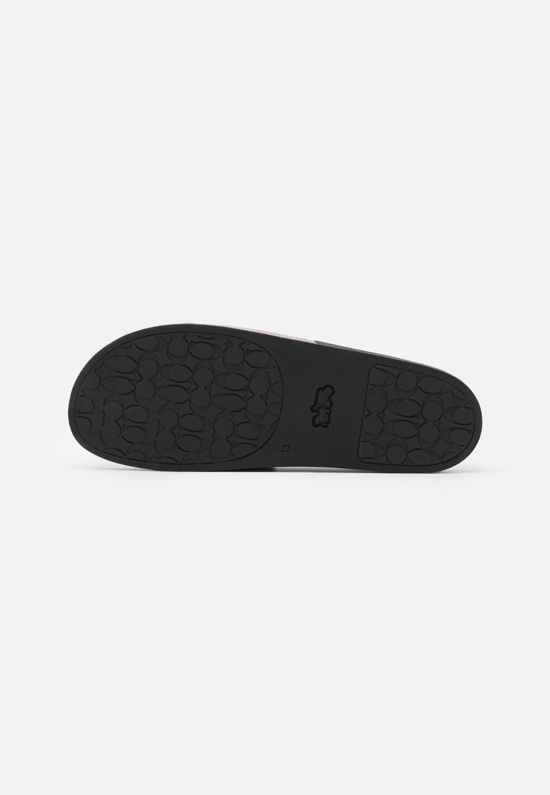 Black rubber outsole with textured circular pattern; side features a light-colored upper with a logo emblem.