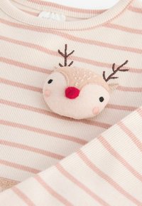 Tissu à rayures crème et rose avec un patch doux représentant un visage de cerf, orné de bois brodés marron et d'un nez rouge.