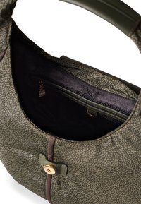 Olive green handbag with a textured exterior, dark fabric lining, zipper pocket, and bronze button closure. Includes leather-like strap accents.