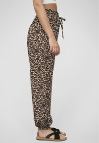 Leopardenmuster-Jogginghosen verfügen über einen elastischen Bund mit Kordelzug, geraffte Bündchen und eine weiche Stofftextur. Getragen mit flachen Sandalen.