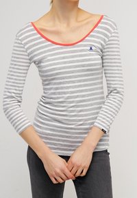 Chemise à manches longues rayée gris et blanc avec un grand col, ornée d'une bordure corail et d'un petit logo bleu sur la poitrine. Tissu extensible.