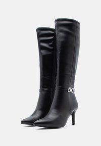 Black knee-high boots made of smooth synthetic leather, featuring a pointed toe, stiletto heel, side zipper, and silver hardware accent.