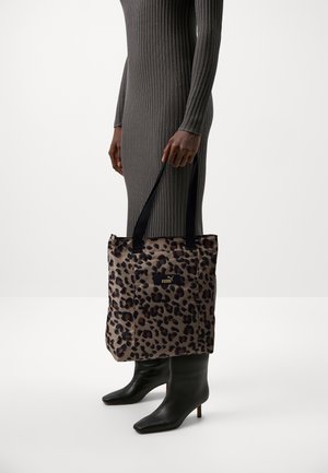 Tote-taske med leopardprint og sorte håndtag, lavet af holdbart stof. Har en gulddetalje med logo og et rummeligt design til at bære ting.