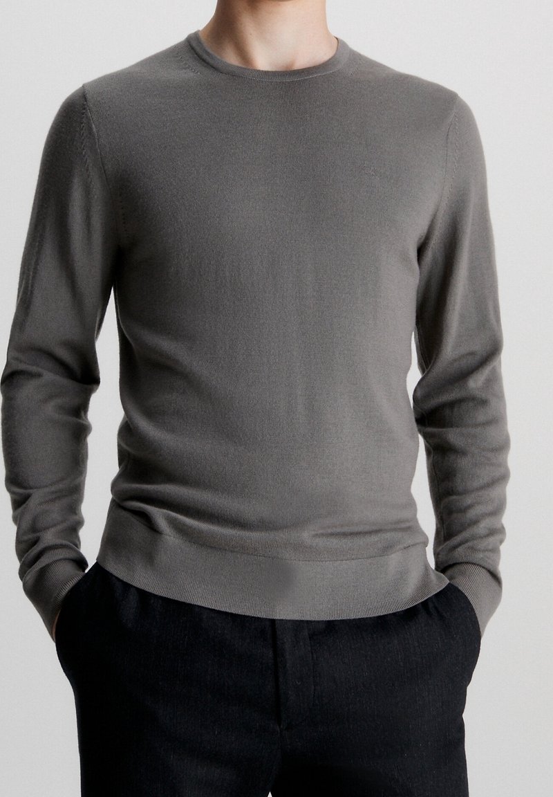 Grauer Langarmpullover aus weichem Strickstoff mit Rundhalsausschnitt, gerippten Bündchen und Saum sowie schlanker Passform.