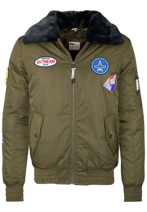 Veste bomber verte avec col en fourrure noire, fermeture éclair frontale, deux poches à rabat et patchs à thème spatial sur la poitrine et les manches.