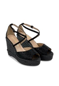 Sandali wedge neri con texture intrecciata e decorazioni luccicanti. Le cinghie incrociate e le punte aperte esaltano il design moderno.