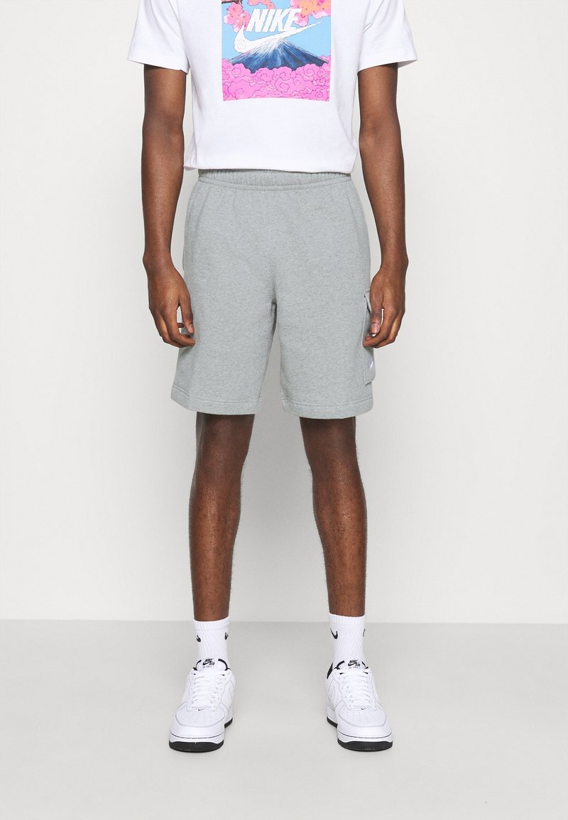 Grå bomullsshorts med ett elastiskt midjeband, sidofickor och logodetalj. Kombinerat med en vit grafisk T-shirt och vita sneakers.