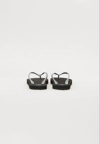 Svarte flip-flops med grå buede stropper og teksturert såle. Flat såledesign som passer til uformell bruk. Ingen merkbare mønstre.