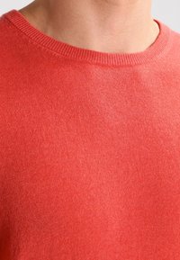 Lekki sweter z koralikowym splotem, z okrągłym dekoltem, charakteryzujący się miękką teksturą i ribbowanym wykończeniem dekoltu. Prosty i minimalistyczny design.