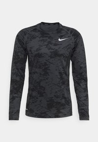 Langärmliges Sportshirt in Schwarz mit strukturiertem Muster, ausgestattet mit einem weißen Nike-Logo auf der Brust und einem Rundhalsausschnitt.