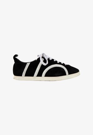Basket en daim noir avec semelle blanche, lacets blancs et détails de bandes blanches courbes et droites sur le côté.