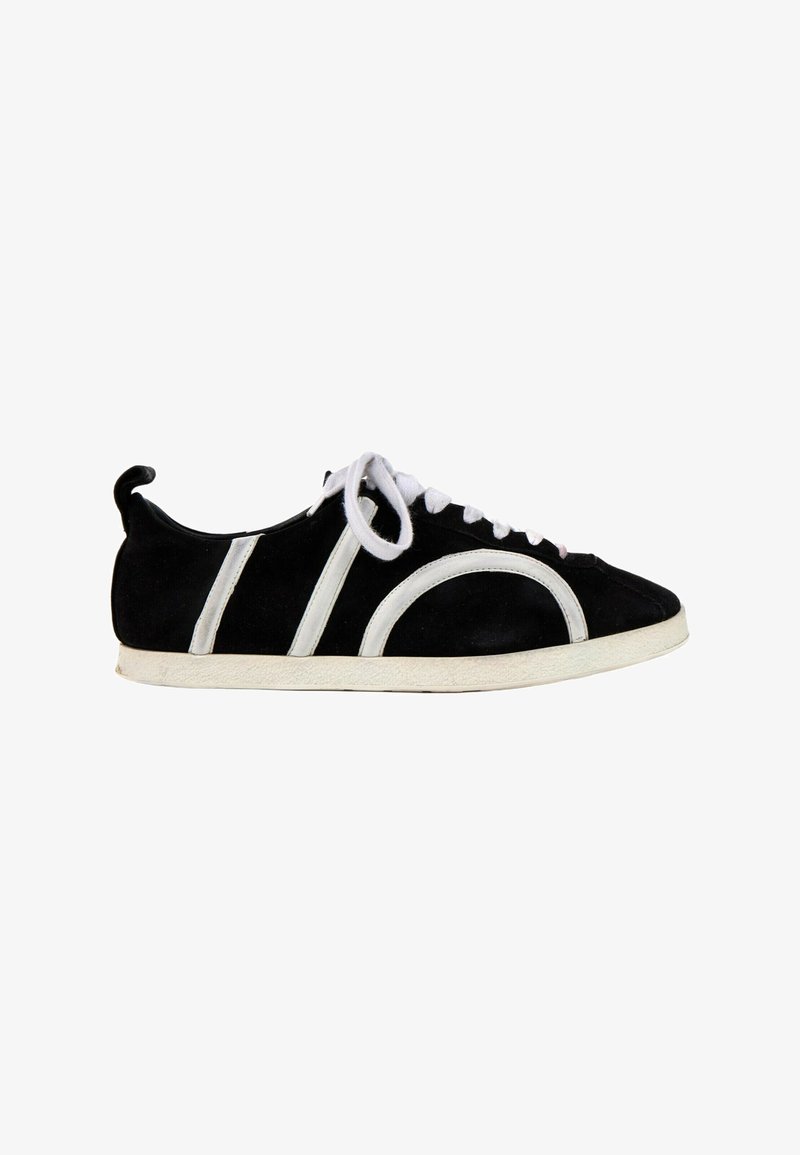 Basket en daim noir avec semelle blanche, lacets blancs et détails de bandes blanches courbes et droites sur le côté.