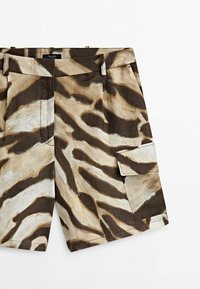 Shorts cargo à imprimé zèbre marron et beige avec passants pour ceinture et une poche à rabat sur la cuisse droite, posés à plat sur un fond blanc.