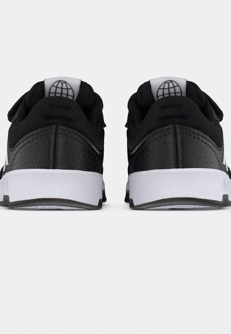 Ein Paar schwarz-weiße Sneakers, von hinten gezeigt, mit gepolsterten Kragen und einem Globus-Logo auf den Fersenlaschen.