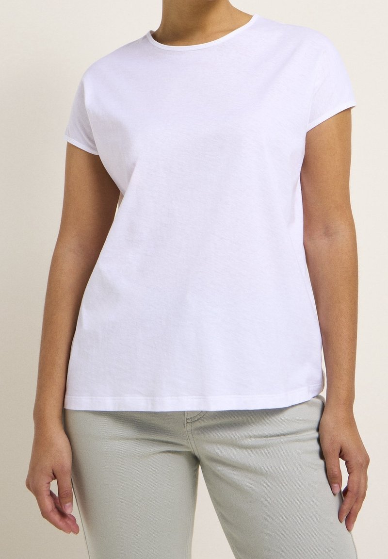 T-shirt bianco in cotone con maniche corte e collo tondo. Il tessuto sembra morbido con una leggera trama e una vestibilità rilassata.