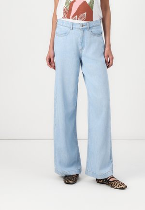 Lys blå vide denimjeans med høy liv, frontlommer og rett kant. Kombinert med en mønstrete skjorte og leopardsko.
