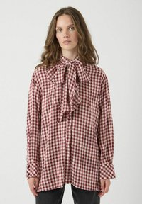 Rood-wit geruite blouse met een grote strik bij de kraag, lange mouwen en knoopmanchetten. Lichtgewicht stof met een losse pasvorm.