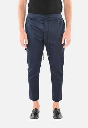 Pantaloni tapered blu navy con cintura elastica, dettagli con cordoncino e tasche laterali. Realizzati in materiale liscio e leggero.
