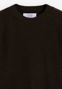 Pulover din lână de culoare maro închis, cu gât înalt ribformat. Are o textură moale și o etichetă cu inscripția "SCALPERS SPECIAL YARN" la guler.