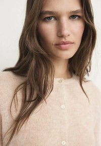 Hellrosa Strickjacke aus weichem, strukturiertem Stoff mit Knopfverschluss und dezentem Glanz. Verfügt über einen runden Ausschnitt und lange Ärmel.