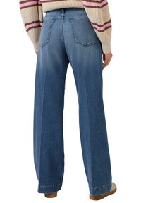 Szerokie dżinsy z niebieskiego denimu o kroju z szerokimi nogawkami, z pięcioma kieszeniami, teksturowanej tkaniny i wysokim pasem. Widoczne przeszycia oraz delikatne przetarcia na nogawkach.