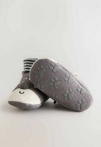 Szare kapcie dziecięce z uroczą twarzą zwierzątka, z miękkiego materiału, w paski na górnej części skarpetki oraz z detalami w kształcie łapek na podeszwie.
