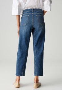 Jeans in denim blu con una vestibilità comoda, dotati di due tasche posteriori e un taglio dritto. Il design comprende un orlo grezzo e una texture sottile.