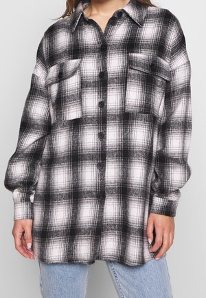 Svart och vit rutigt flanellskjorta med två framfickor, knäppning framtill och långa ärmar. Mjuk textur, avslappnad passform.