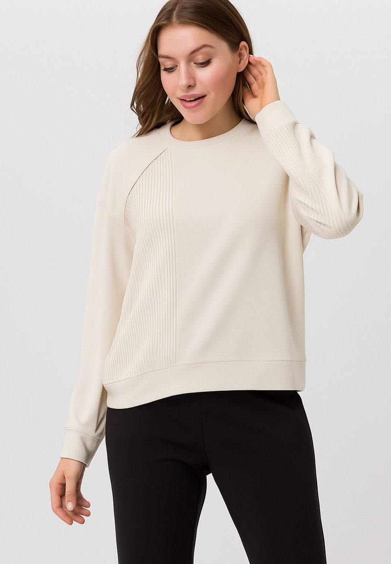 Lichtbeige sweater met lange mouwen, met aan één kant een geribbelde textuur en een gladde afwerking. Losse pasvorm en ronde hals.