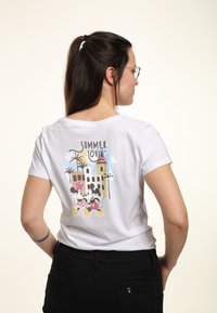 Weißes Baumwoll-T-Shirt mit dem Grafikdruck "SUMMER LOVIN'" und Illustrationen von Mickey und Minnie Maus, Palmen und einem Gebäude auf der Rückseite.