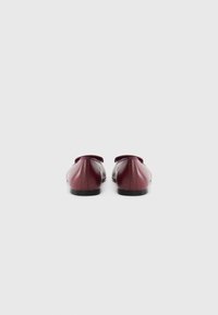 Burgundy leather shoes with a smooth finish, rounded toe, and a flat black sole. Back view shows no visible hardware or accents.