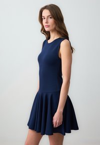 Robe sans manches bleu marine en tissu doux, avec un corsage ajusté et une jupe évasée, texture lisse et décolleté rond.