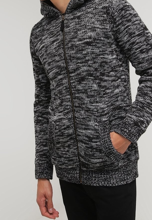 Knitted zip-up hoodie in black and white marled pattern, features a front zipper, two side pockets, and a fitted hem and cuffs.