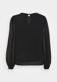 Blouse noire avec manches longues transparentes, encolure ronde, et ouverture goutte d'eau dans le dos fermée par un petit bouton. Finition en tissu lisse.