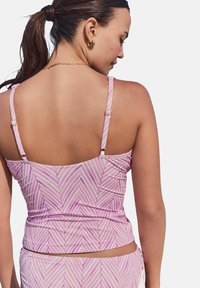 Débardeur rose avec des rayures blanches diagonales, bretelles ajustables et texture froncée. La vue arrière montre un design simple et épuré sans embellissements.