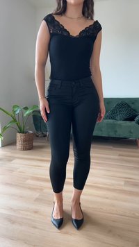 Body preto com detalhes em renda nas mangas, combinado com jeans skinny pretos e sapatos de salto altos pretos com bico fino. Silhueta elegante e ajustada.