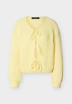 Μαλακό κίτρινο πλεκτό ζακέτα με μακριά μανίκια, ριμπ μανσέτες και τελείωμα, με τρία μπροστινά κλεισίματα με κορδόνια.