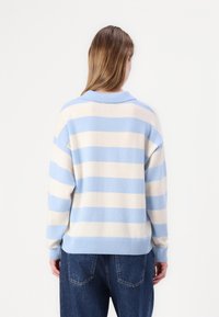 Blue and cream striped sweater made of soft fabric, featuring a collar and ribbed hem. Relaxed fit with a casual design.