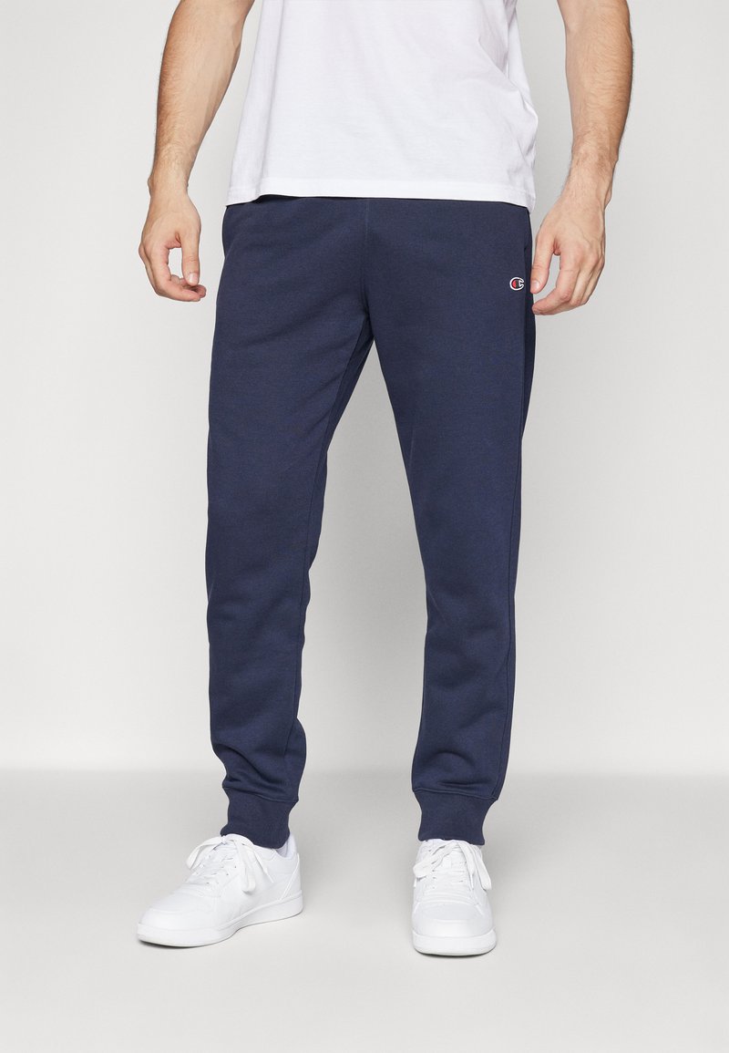 Marineblaue Sweatpants aus weichem Material, mit einem elastischen Bund und Bündchen, einem kleinen Logo am linken Oberschenkel und einem lässigen Schnitt.