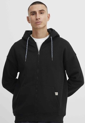 Zwarte zip-up hoodie met een trekkoordcapuchon, zijzakken en een label aan de zoom. Kenmerkt zich door een gladde textuur en een relaxed fit.