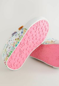 Chaussures en toile colorées avec un motif floral en violet, bleu et vert, dotées d'une semelle rose à motifs étoiles et d'accents blancs.