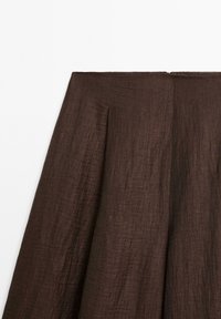Hnědá, strukturovaná sukně s vysokým pasem, obsahující skladby a skrytý zip na zadní straně. Hladká, lehká látka.