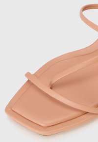 Beige firkantet tå sandal med slanke stropper, polstret såle og glatt lærtekstur.