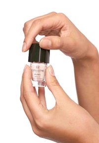 Lo smalto Collistar in un flacone di vetro trasparente con un tappo nero, tenuto in mano. Il colore appare rosa chiaro con una finitura lucida.